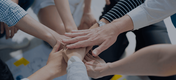 Banner image of team members hands in circle, for blog on community volunteering