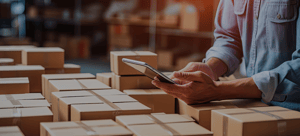 Warehouse worker using tablet near a number of packed boxes